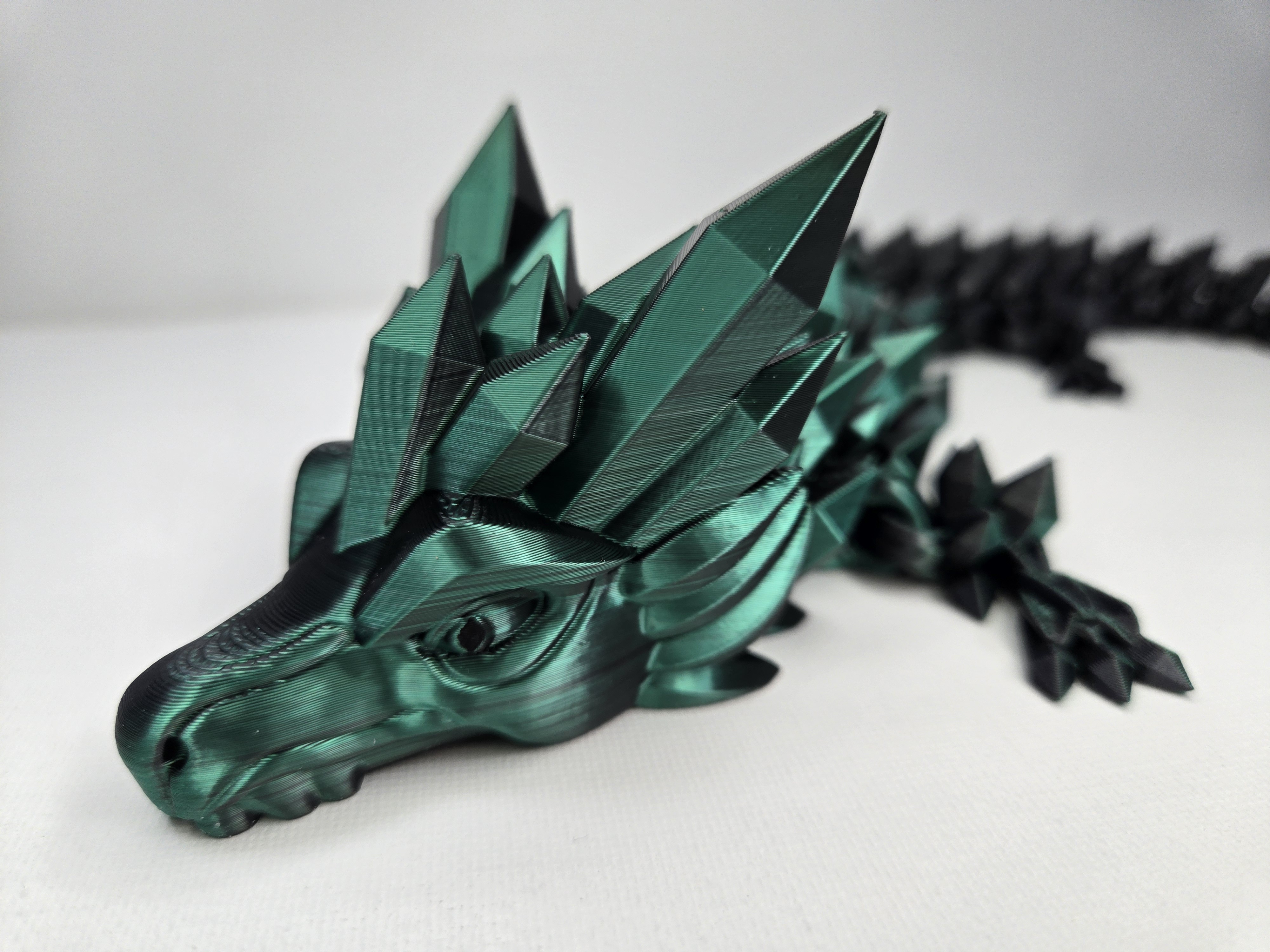3D printed emerald green crystal dragon with faceted geometric head and articulated body