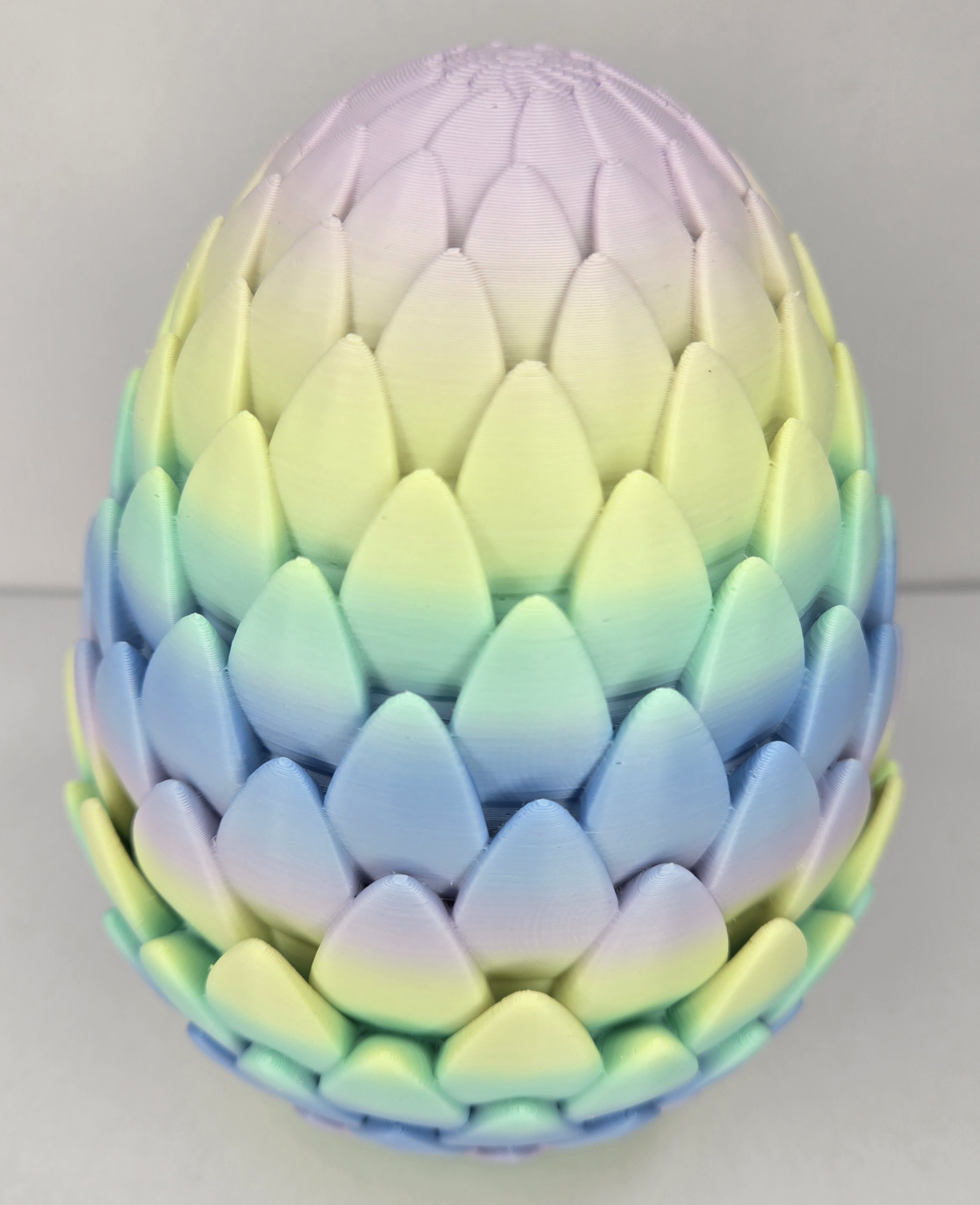 3D printed dragon egg in rainbow pastel colours, scale-textured and closed