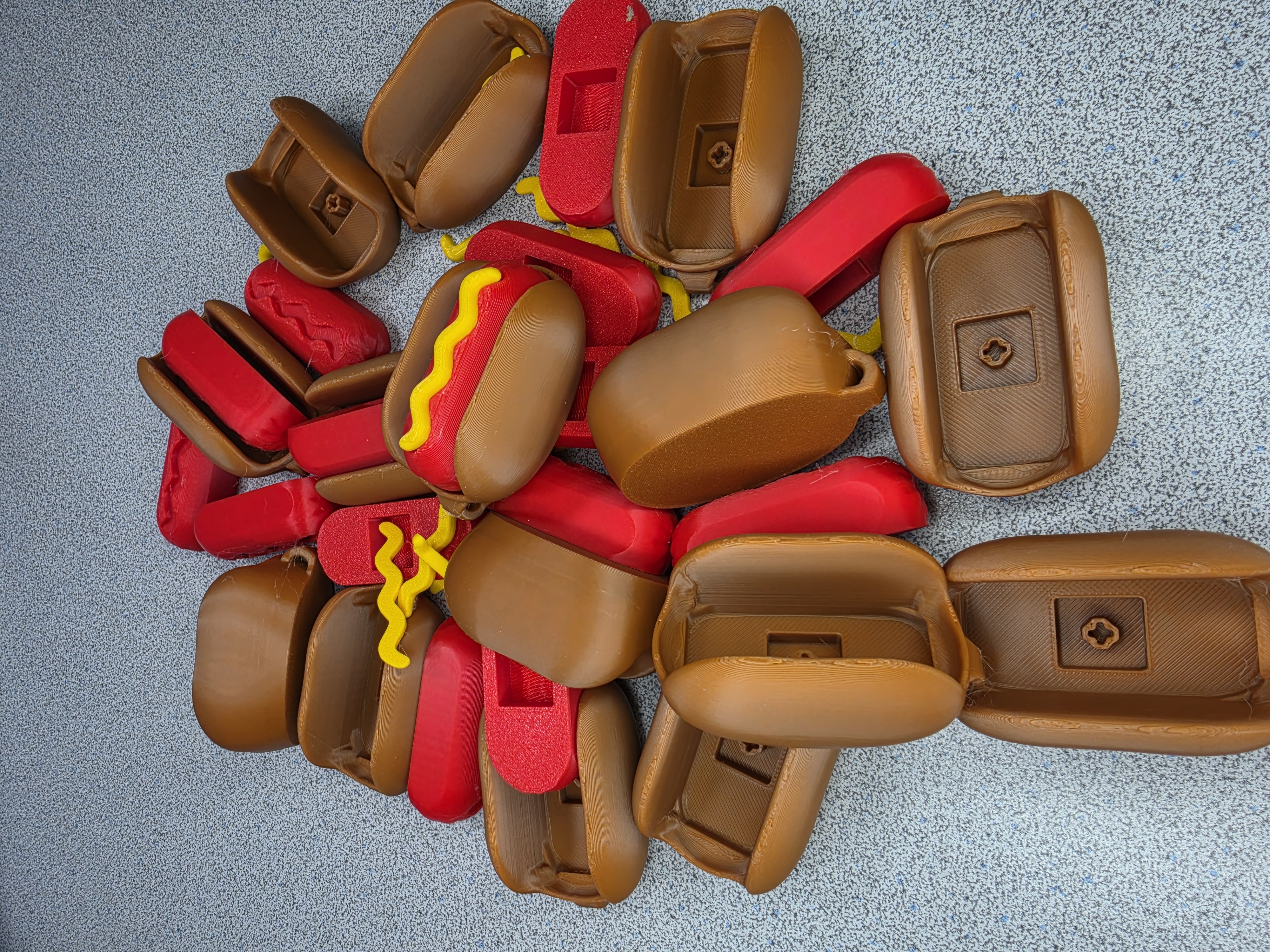 Batch of 3D printed hot dog shaped cases in brown, red and mustard yellow
